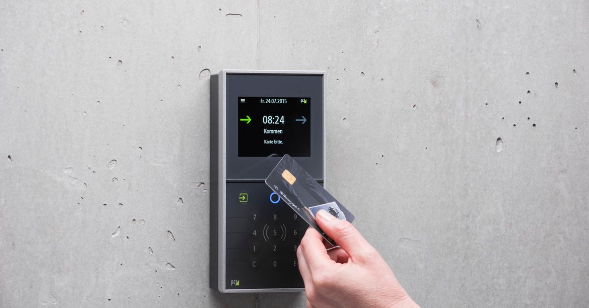 A man holds an access card to a wall-mounted card reader beside a concrete wall.