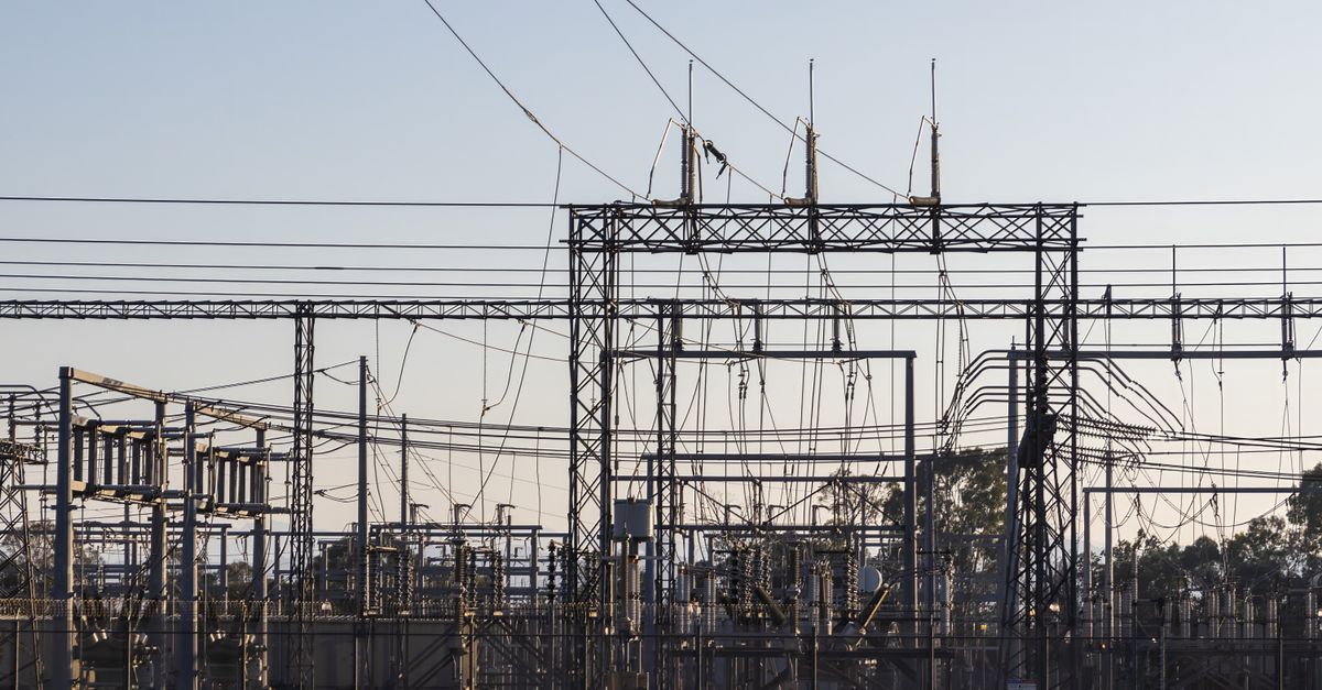 High-voltage substation with steel lattice structures and power lines at dawn
